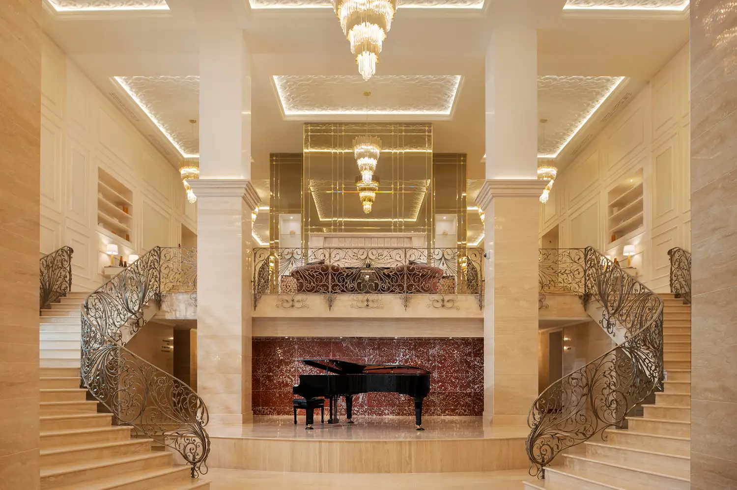 The grand lobby of Ayan Zalaat featuring a spiral staircase, a central piano, and marble flooring.