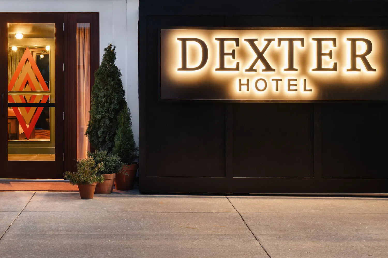 Exterior view of the Dexter Hotel entrance and illuminated signage.