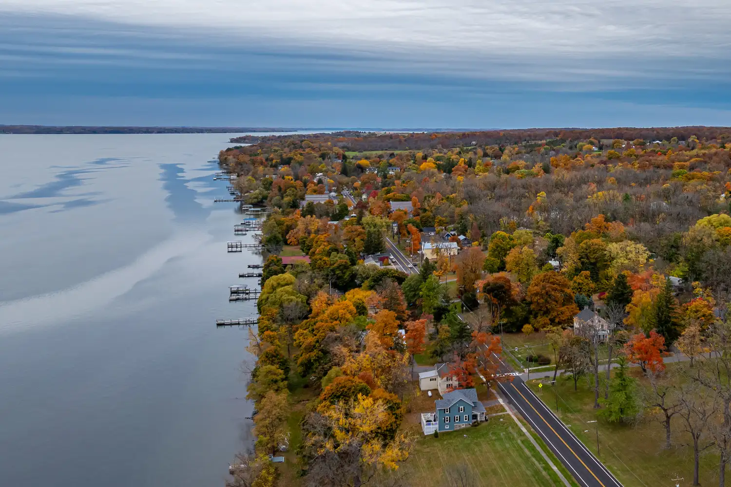 Aerial perspective of Aurora, New York, showing houses along the shore surrounded by vibrant fall foliage.