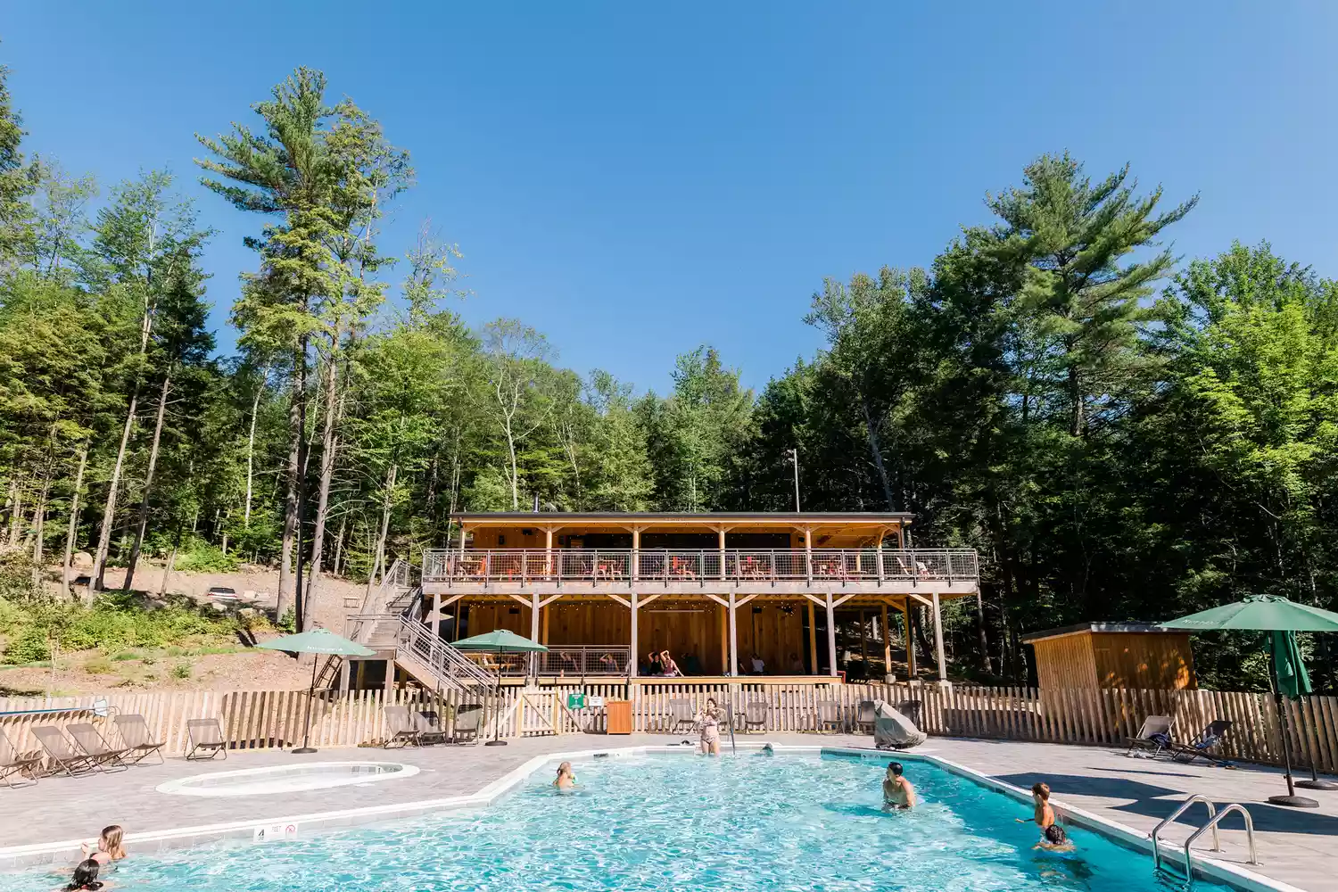 Families relaxing in a swimming pool at the Huttopia glamping resort.