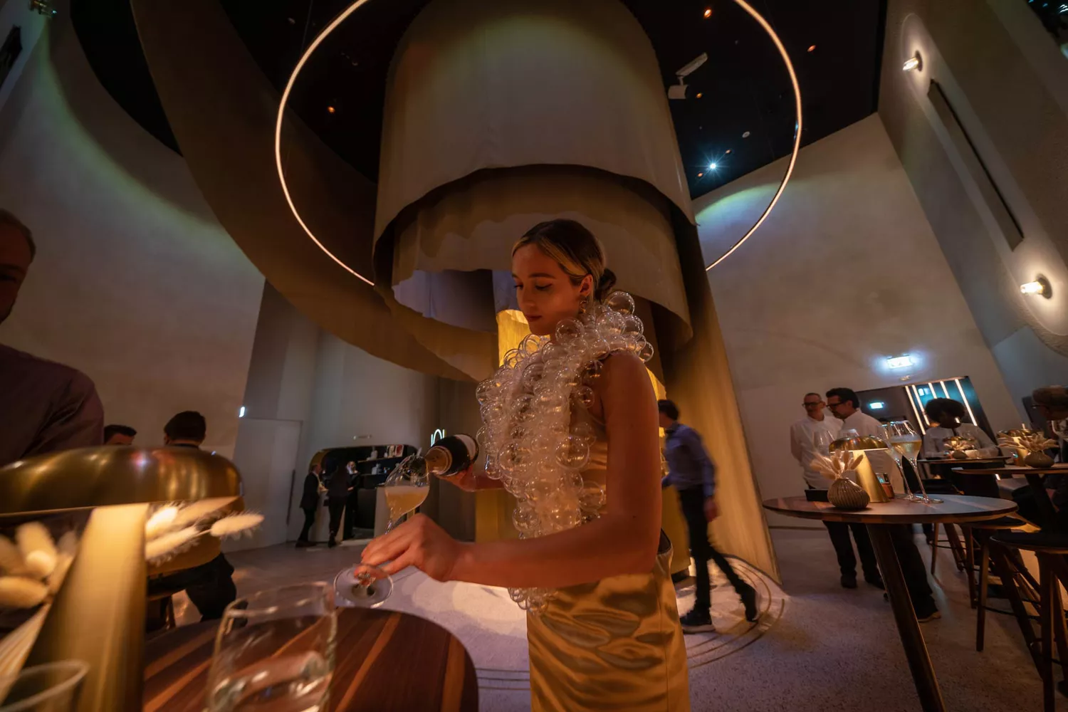 A performer at Eatrenalin wearing a custom-designed dress that serves as a holder for multiple champagne glasses.