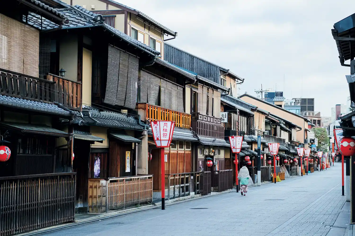 A traditional wooden street in Gion Kyoto with red lanterns and few pedestrians.