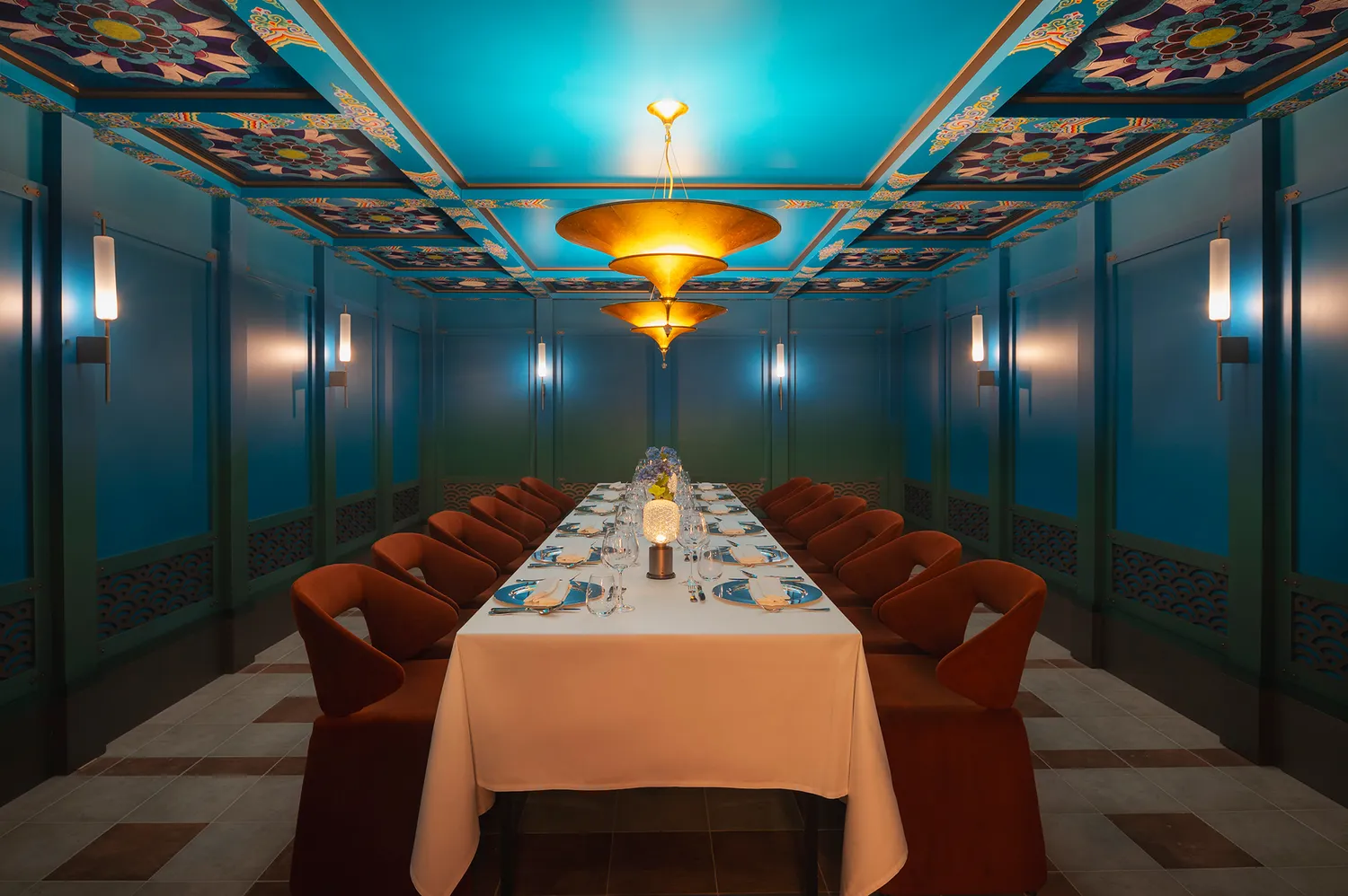 A long dining table set inside the Soma Temple with ornate blue walls and highly decorative ceilings.