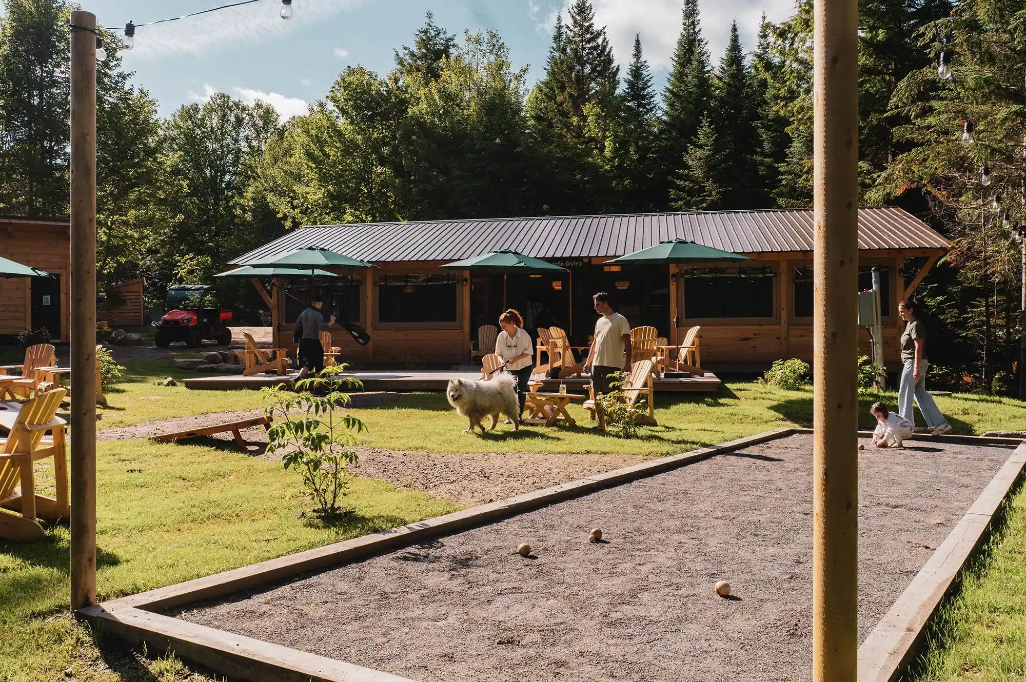 Guests playing lawn games near a large wooden central building surrounded by vibrant green grass and trees.