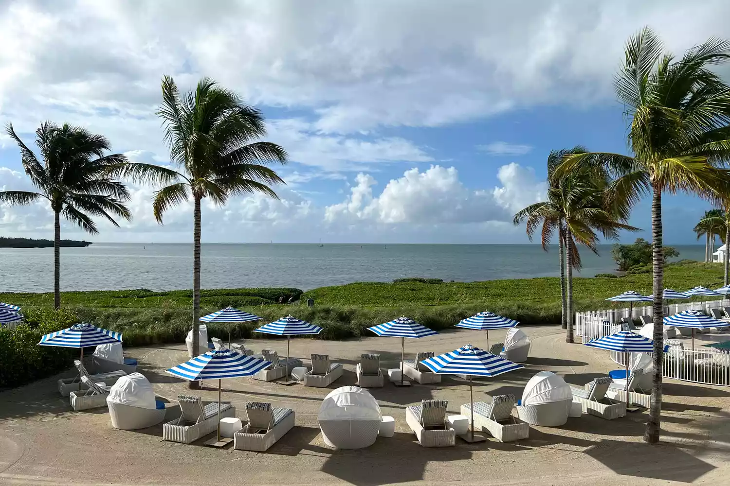 Woven beach lounge chairs on the sand looking out to the ocean at Isla Bella Beach Resort.