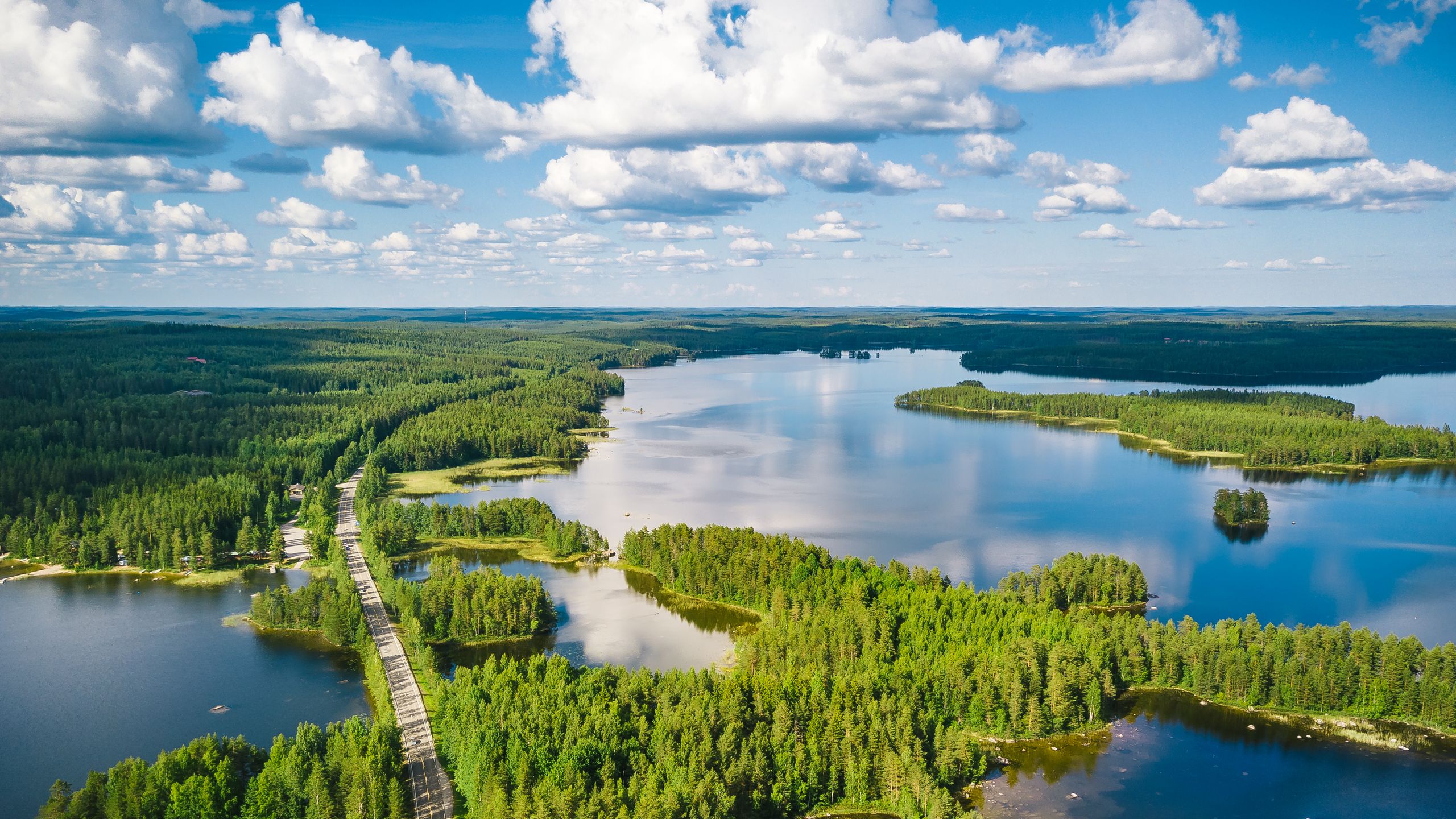 Aerial high-angle view of the Finnish Lakeland featuring dense green forests and interconnected water bodies.