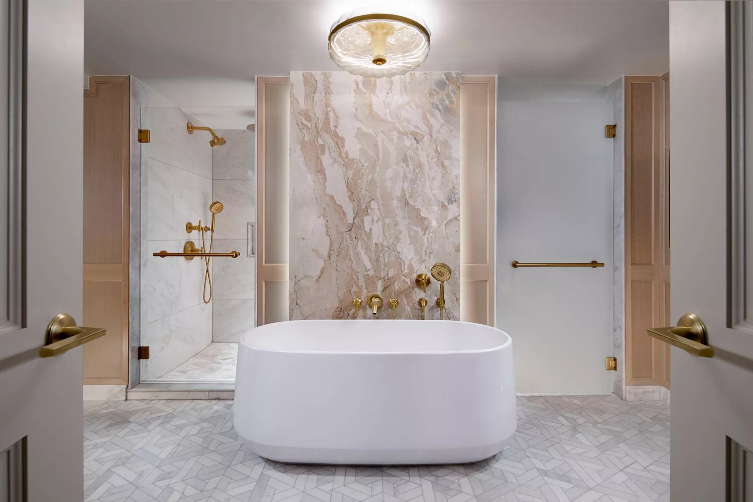 A luxurious marble bathroom featuring a deep soaking tub and a dedicated glass shower.