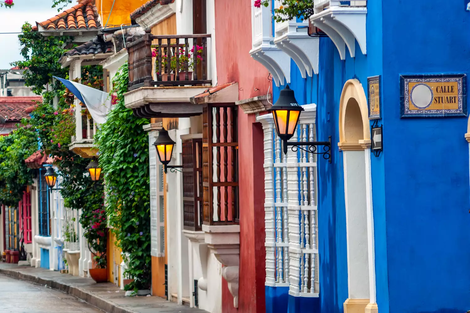 Brightly colored colonial buildings with floral balconies on a street in Cartagena, Colombia.