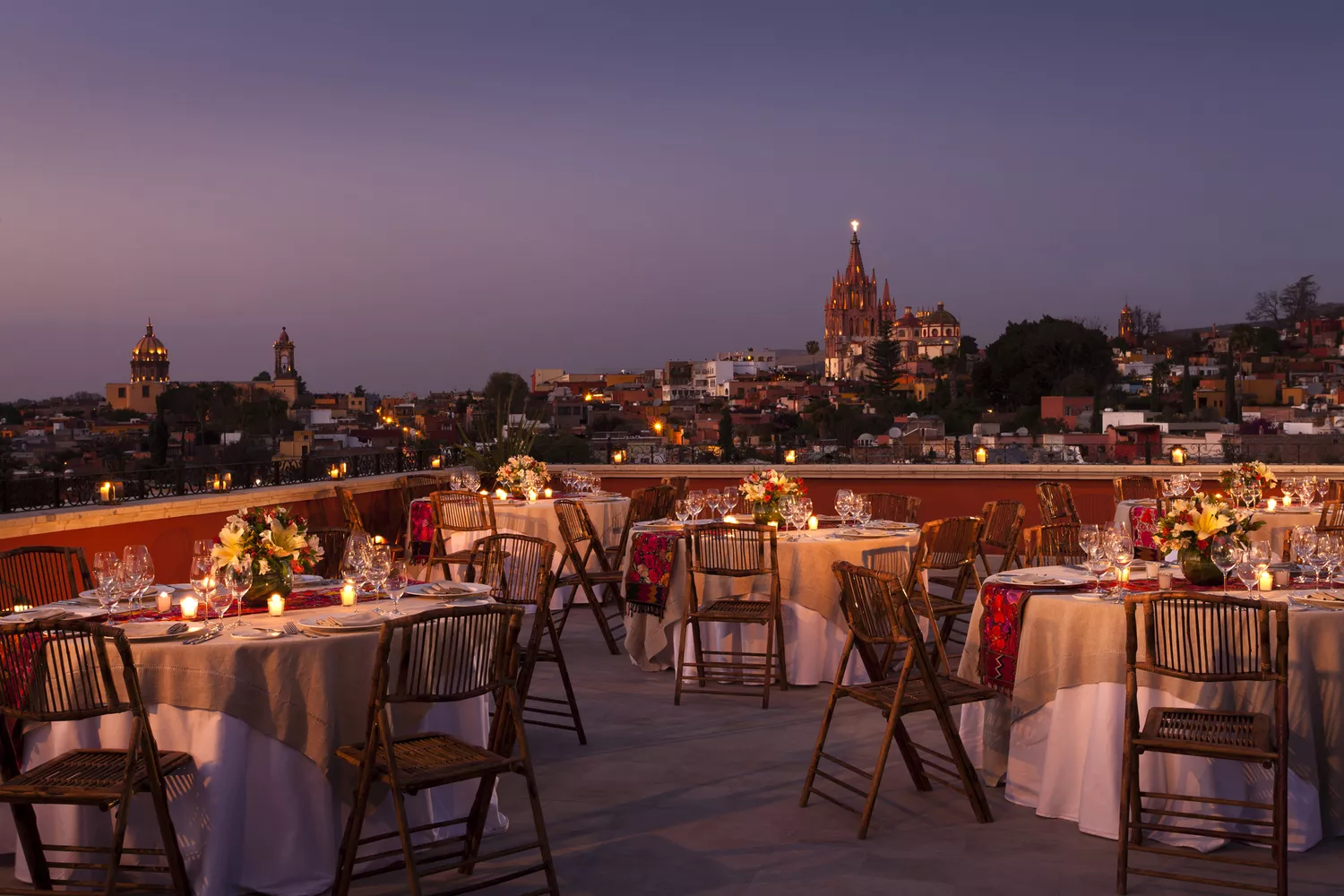 Elegant rooftop restaurant setting with an umbrella and views of colonial church spires in San Miguel de Allende.