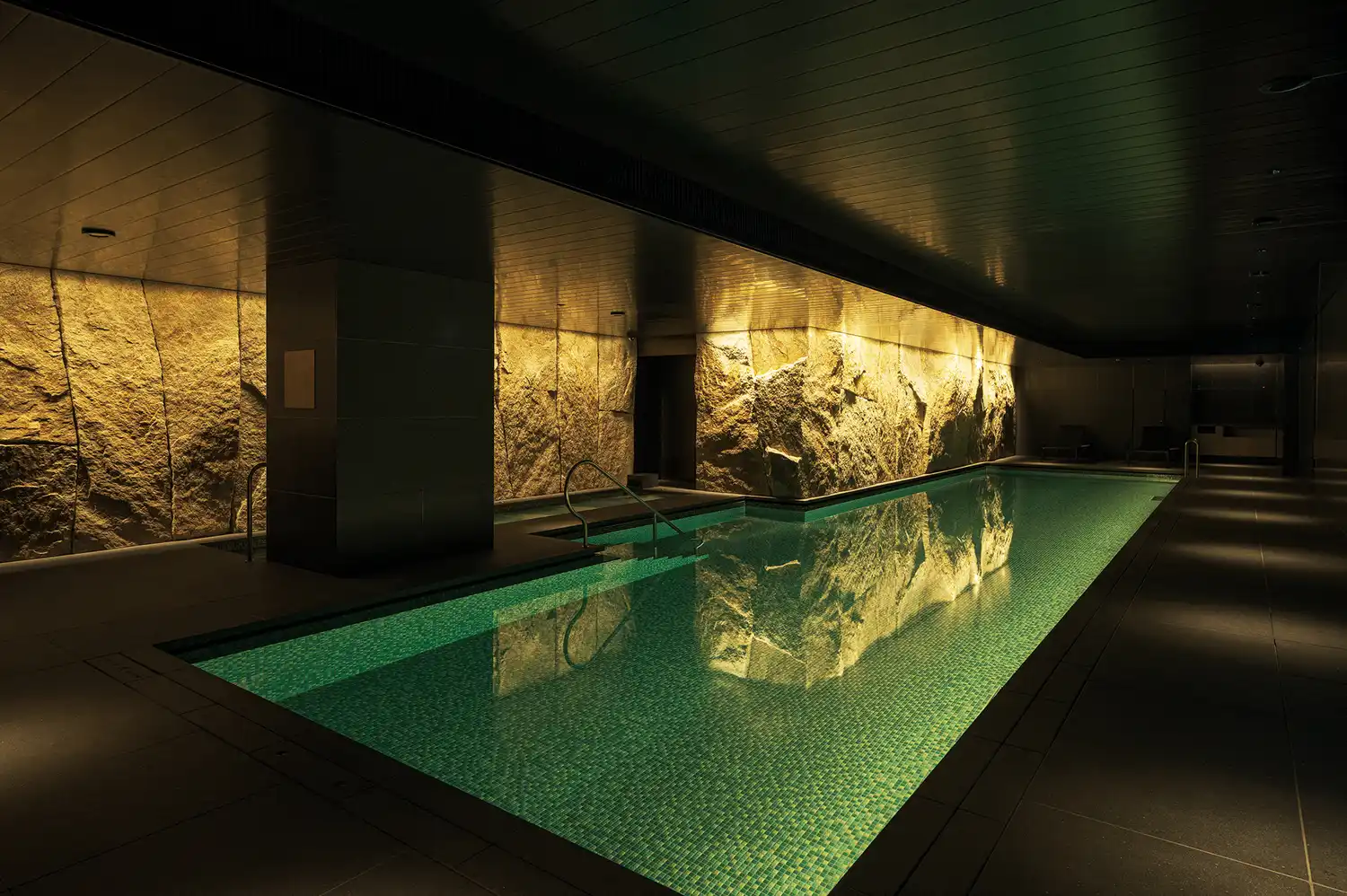 Indoor swimming pool with modern geometric light patterns on the walls.