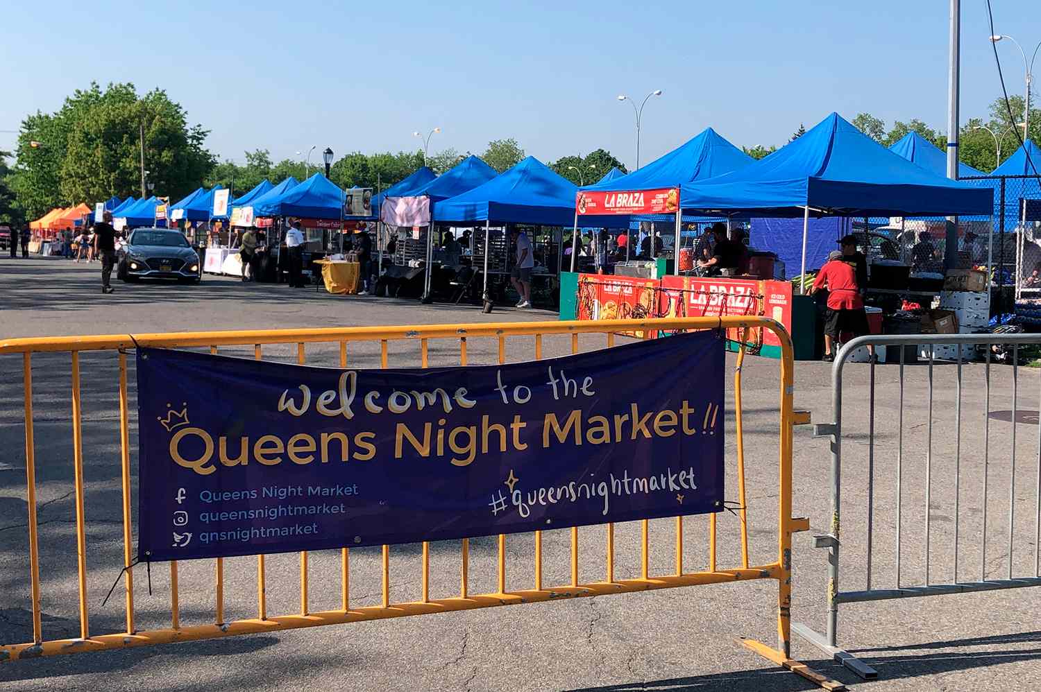 Close-up of various international street food stalls with diverse signage and customers at the Queens Night Market.