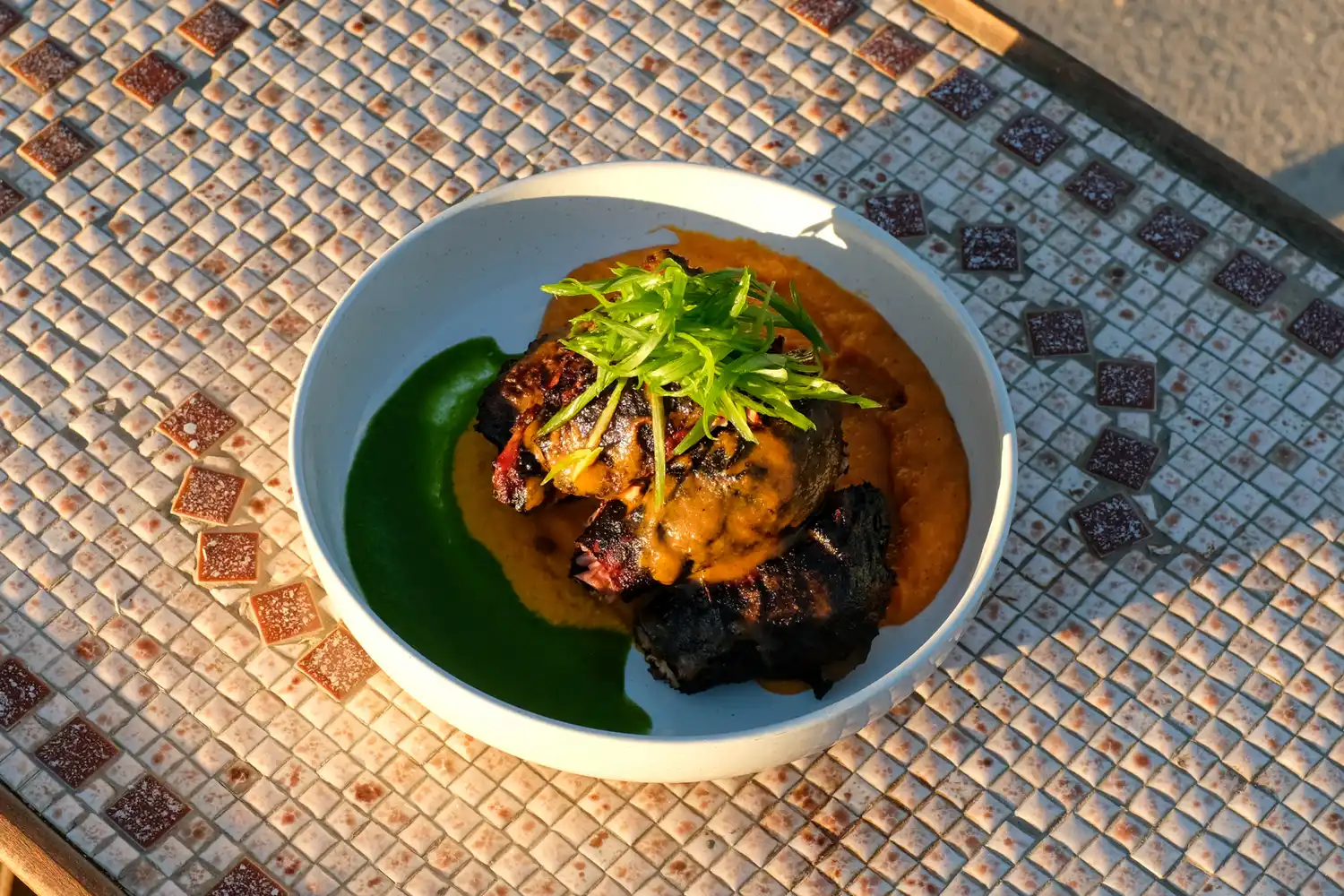A gourmet dish with sauces and garnishes served on a rustic blue tile surface.