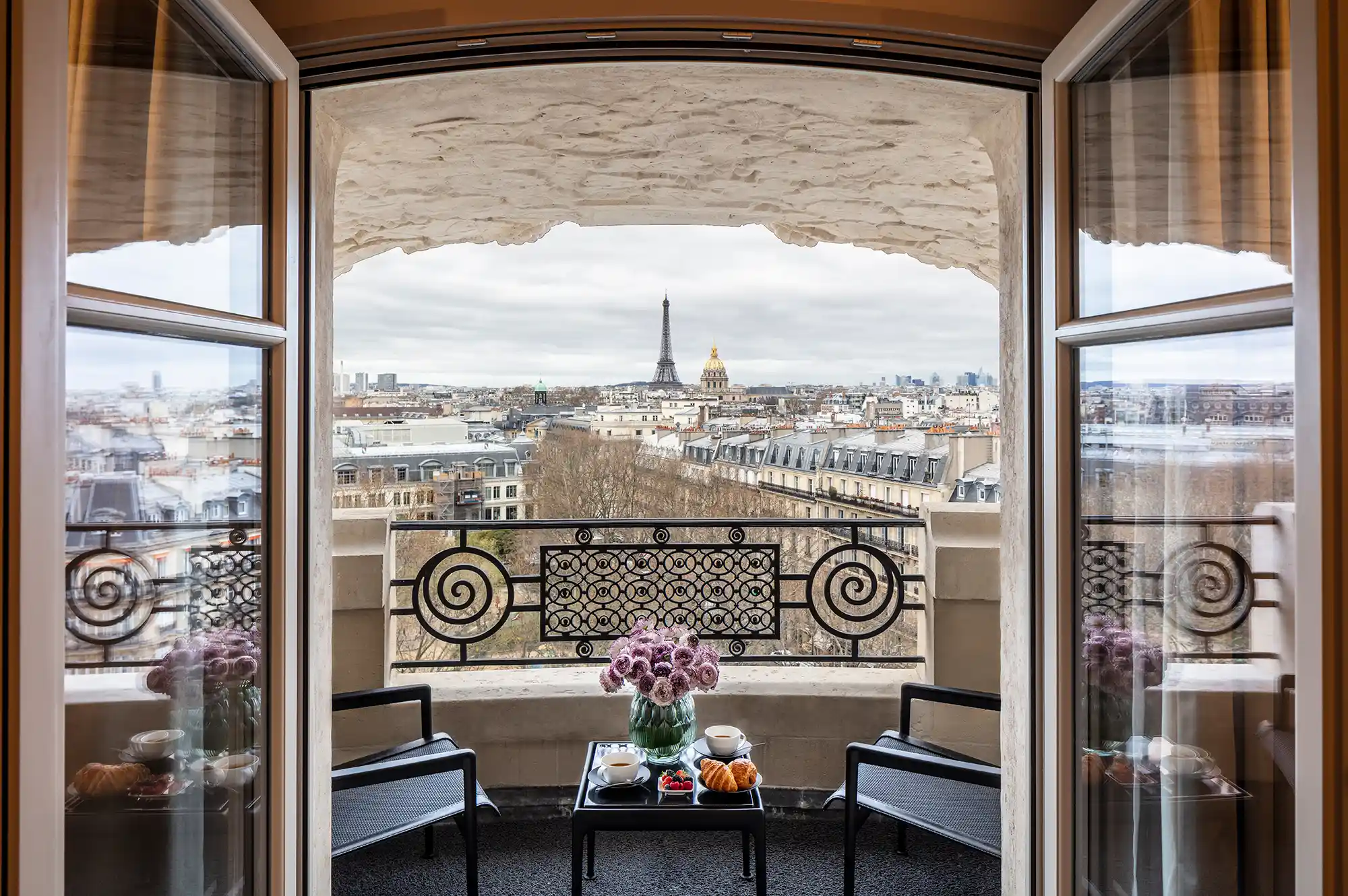 A balcony view looking out over Parisian rooftops toward the Eiffel Tower.