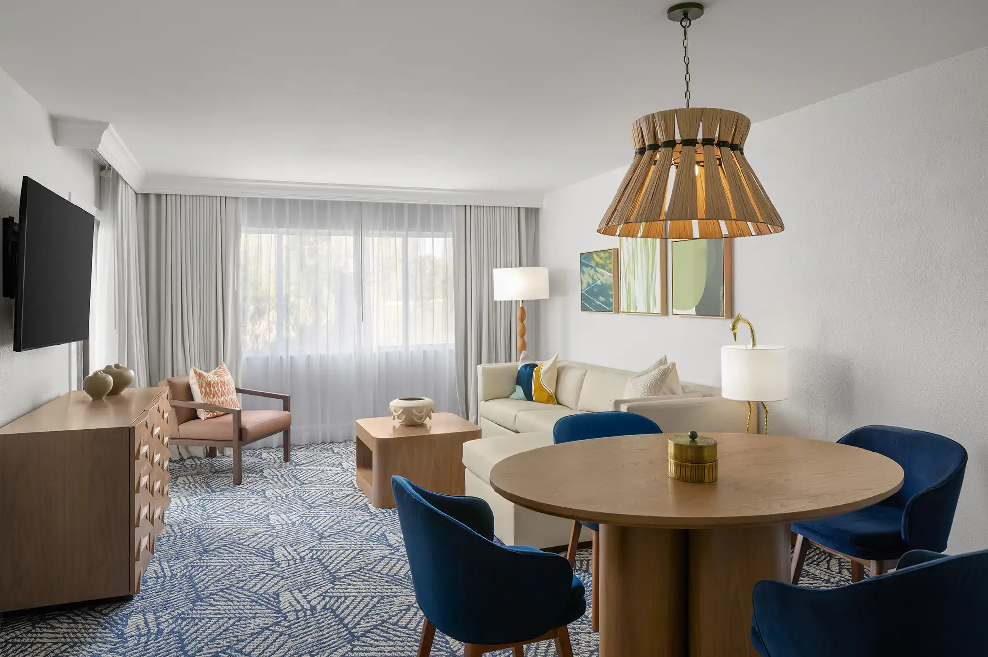 A modern living room in a resort suite with blue dining chairs, contemporary coffee table, and soft wood tones.