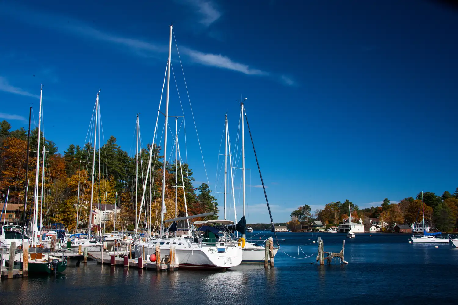 A marina in Gilford, New Hampshire, filled with sailboats under a clear blue sky.