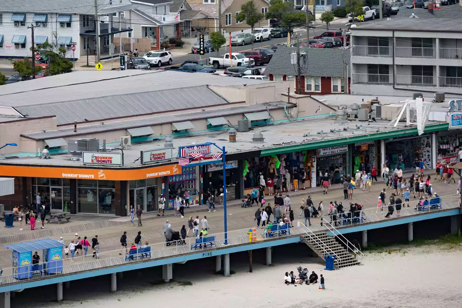 Crowds of visitors walking through the expansive Wildwood boardwalk during a sunny day.