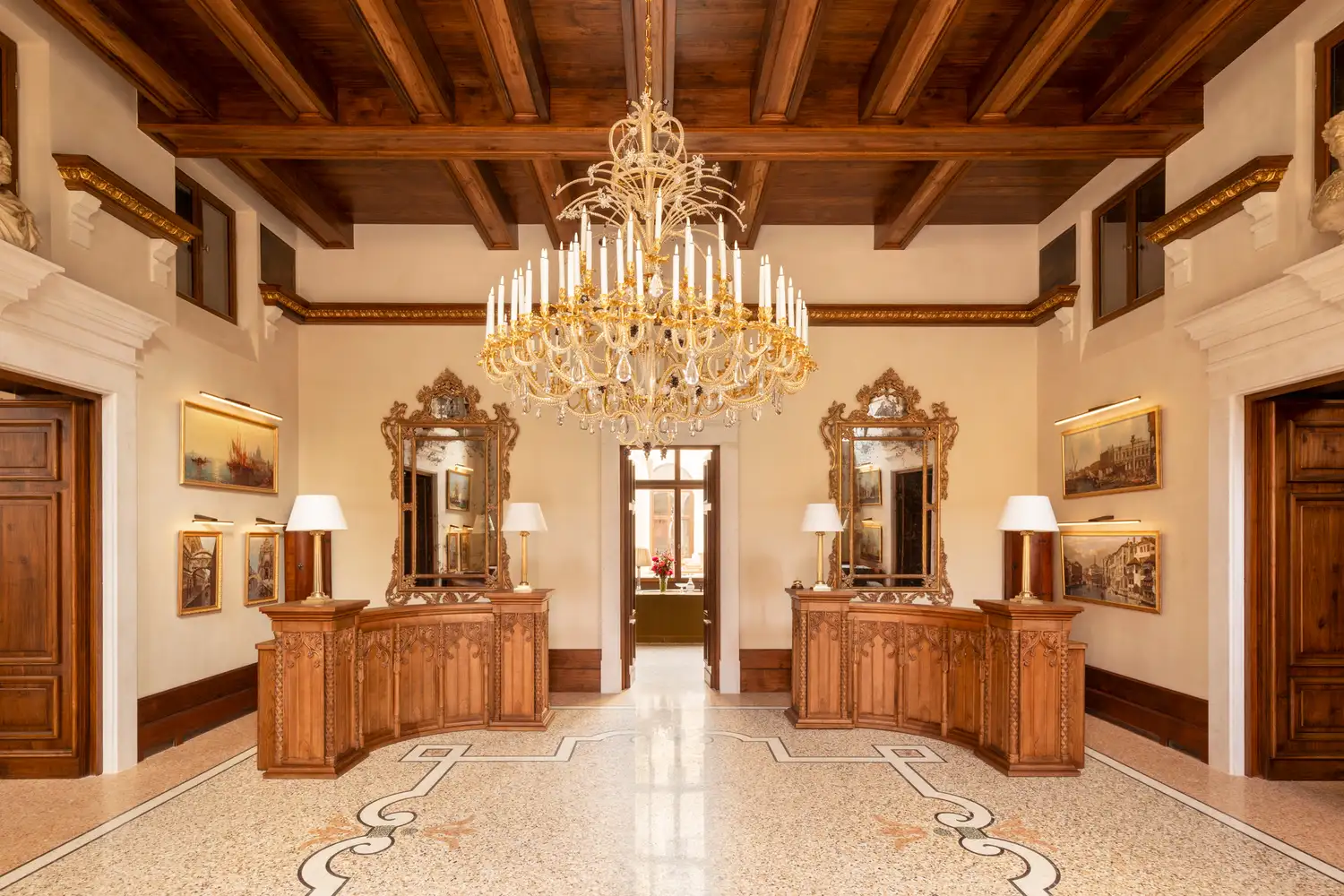 The elegant lobby of Airelles Palladio Venice featuring wooden desks and ornate Venetian mirrors.