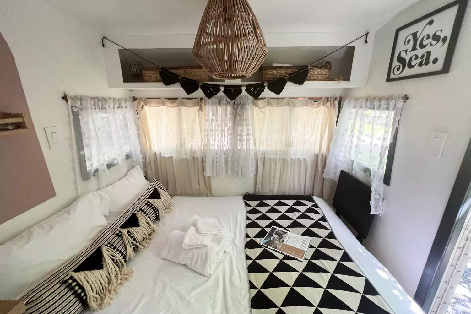 Inside the Rosa glamping trailer at Boheme Retreats featuring a comfortable bed and vibrant textiles.