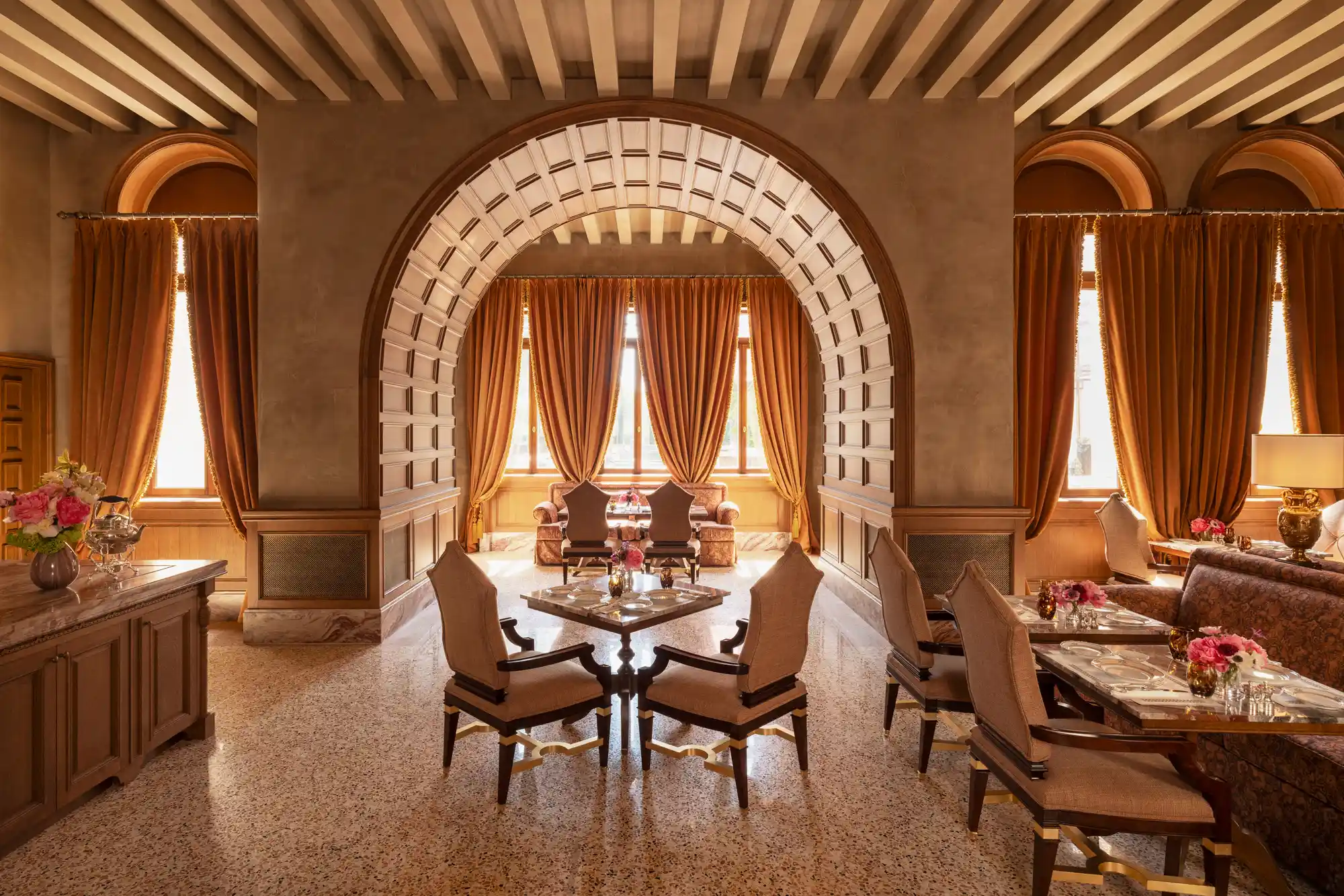 The light-filled dining room at Airelles Palladio with large windows and elegant table settings.