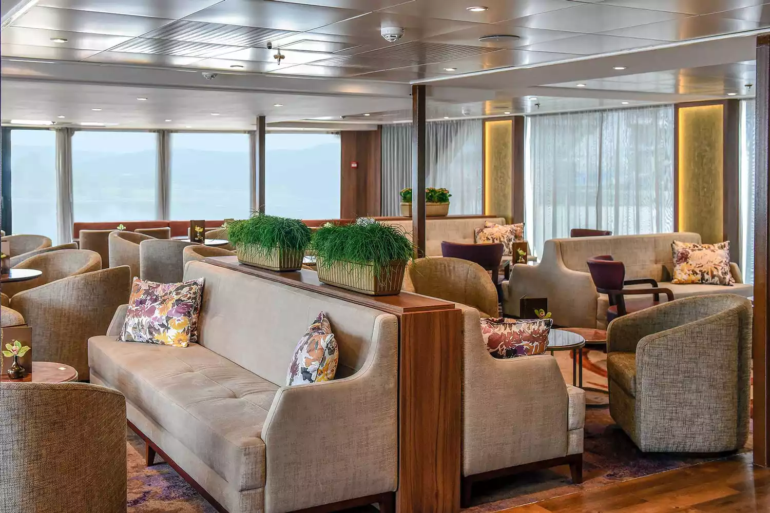 The bright and contemporary lounge area of an AmaWaterways river cruise ship featuring plush seating and large windows.