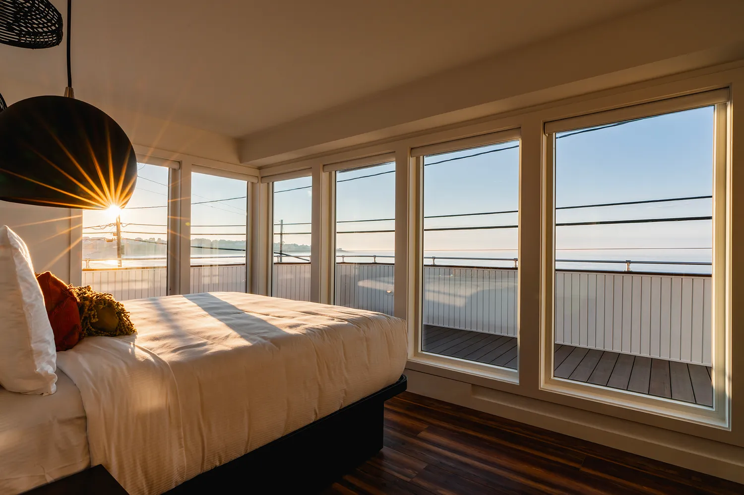 Interior view of the Glass Corner Guest room at The Nevada Hotel showing floor-to-ceiling windows overlooking the ocean.