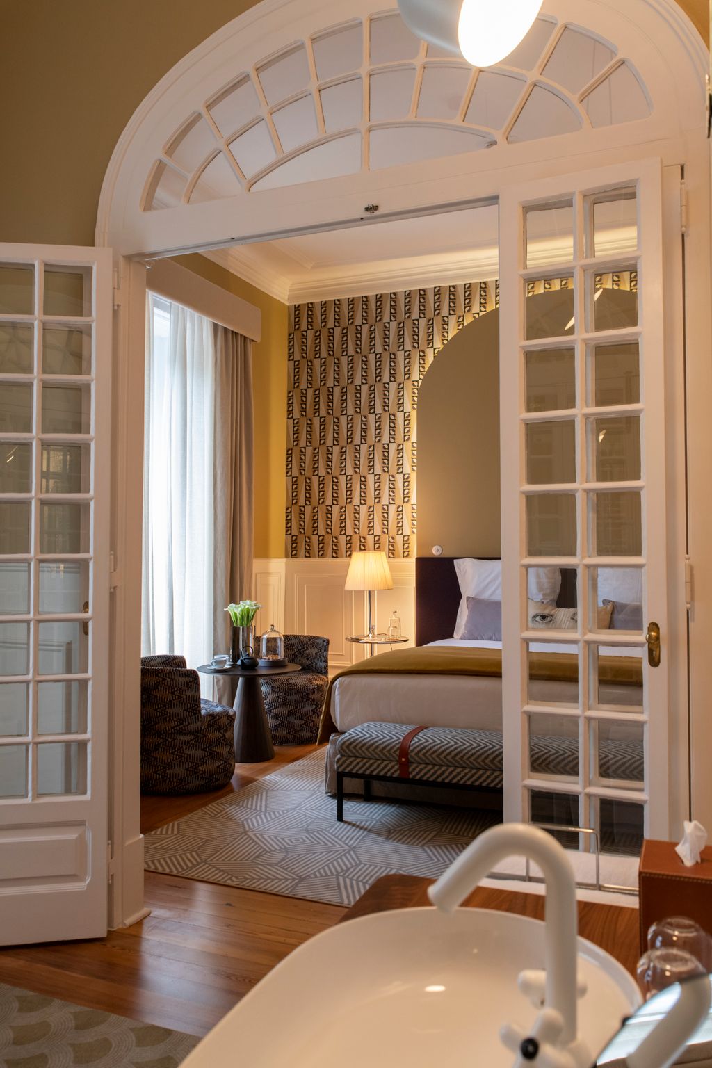 A luxurious bedroom suite at Sublime Lisboa featuring high ceilings and elegant furnishings.