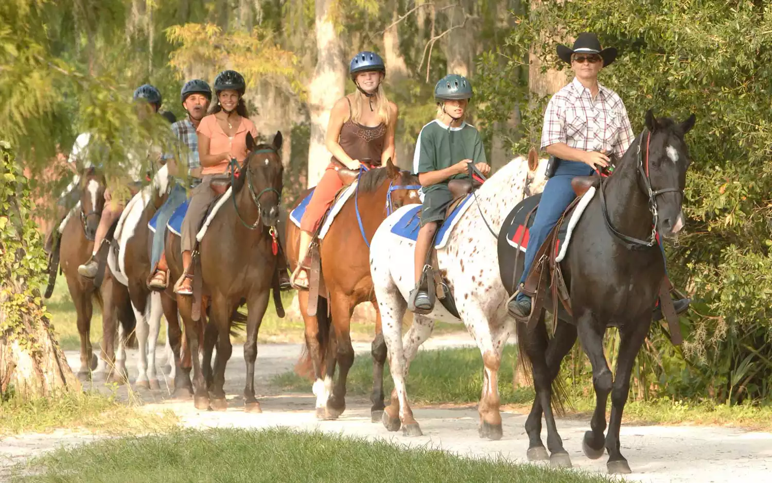 A family enjoying a guided horseback riding excursion through the trails at Fort Wilderness.