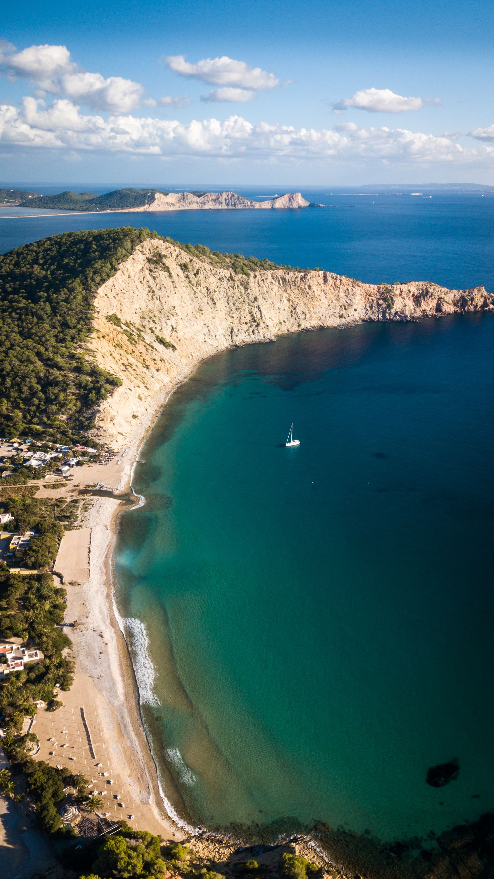 Boats anchored in a secluded rocky bay with lush green Mediterranean vegetation.