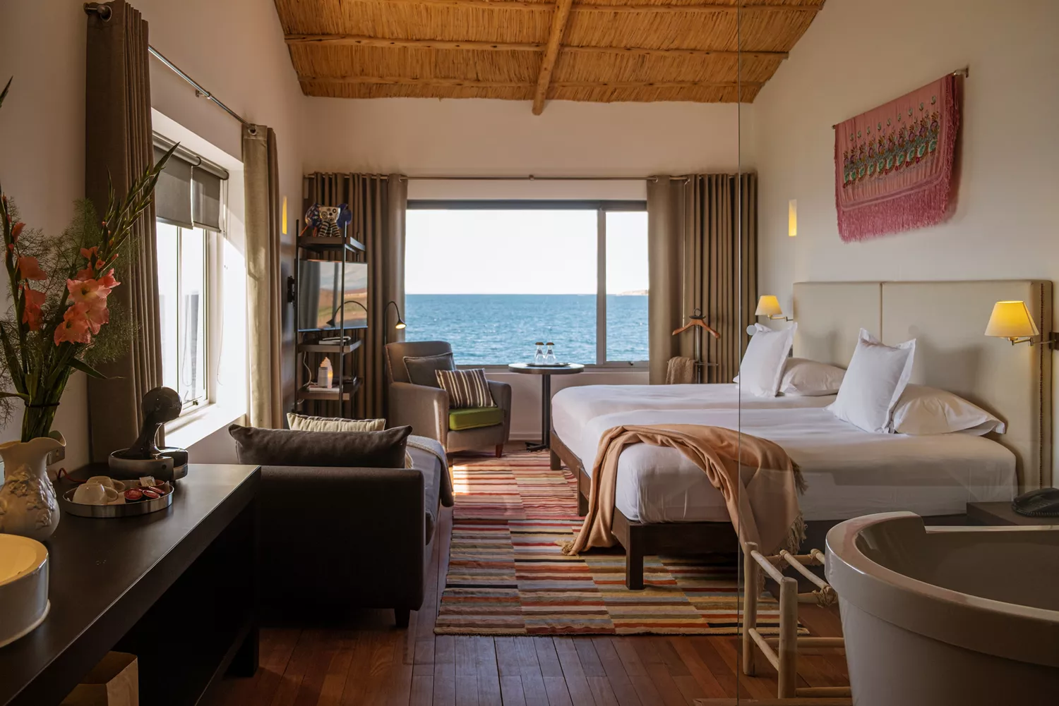 Interior of a luxury hotel room at Titilaka with neutral-toned bedding and large windows facing Lake Titicaca.