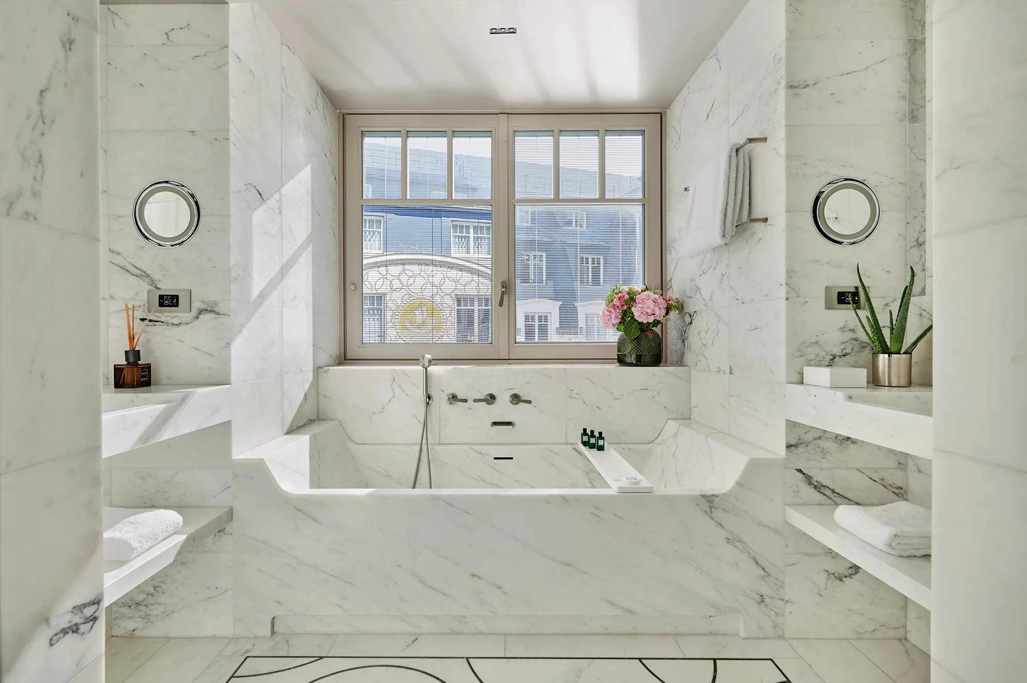 A bright luxury bathroom with a large soaking tub and double marble sinks.
