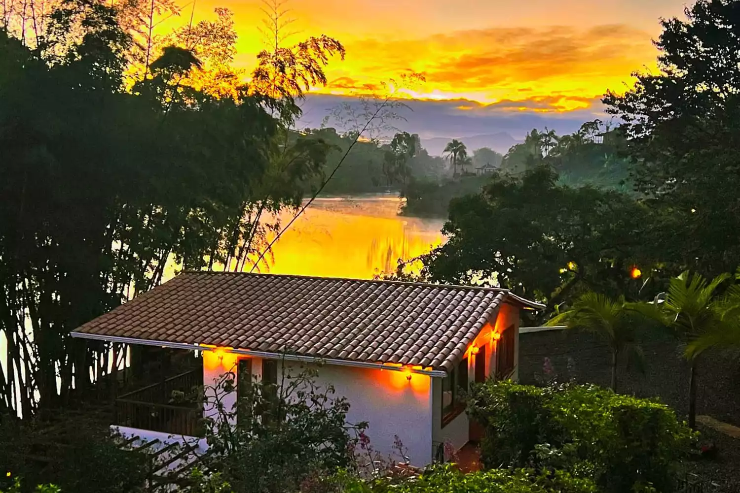 Exterior view of Casa Eve Hotel in Guatape during a golden hour sunset over the lake.