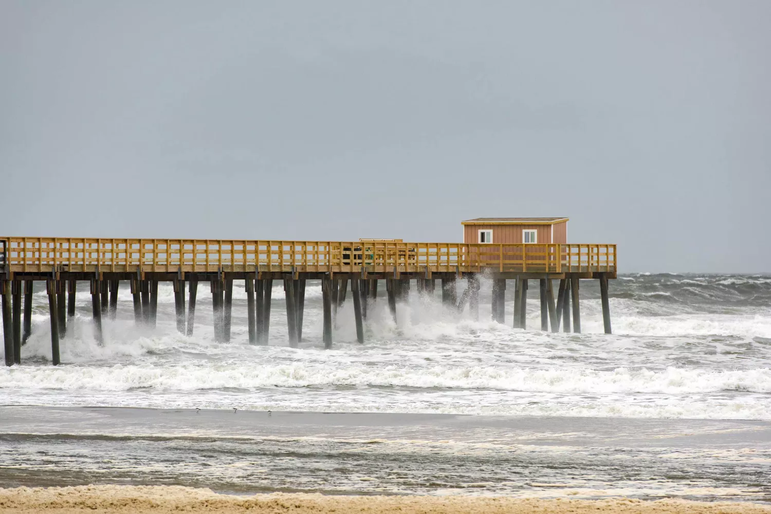 A serene fishing pier extending into the Atlantic Ocean from a quiet New Jersey beach.