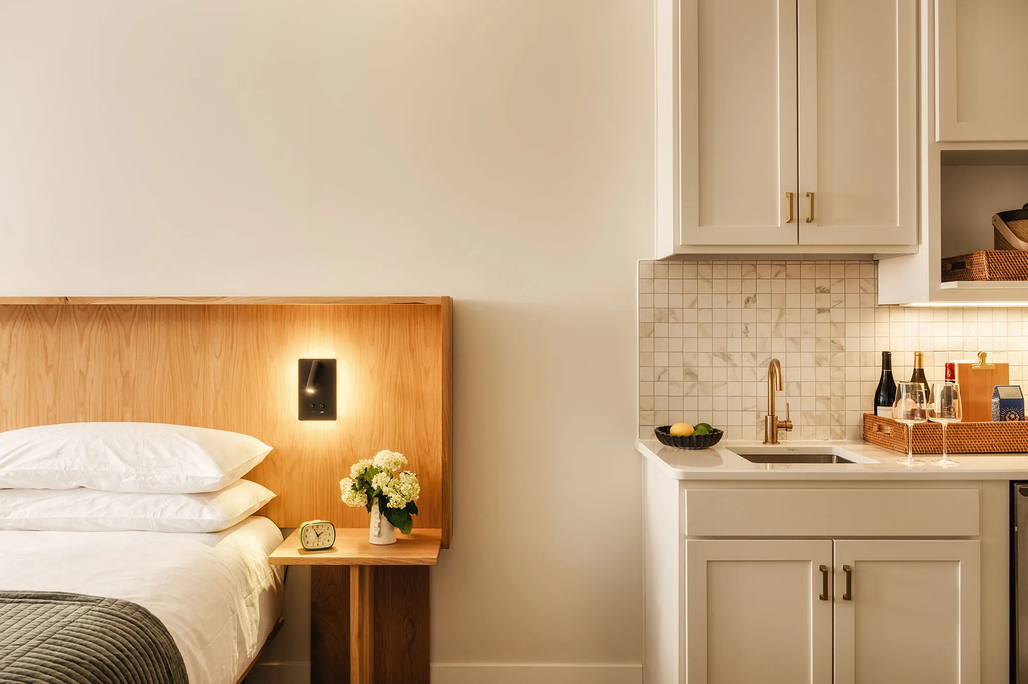 Guest room with custom wooden headboard and a built-in kitchen area.