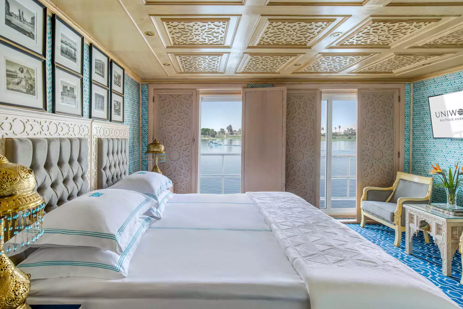 A lavishly decorated boutique guest room on a Uniworld river cruise ship with fine linens and antique-style furnishings.