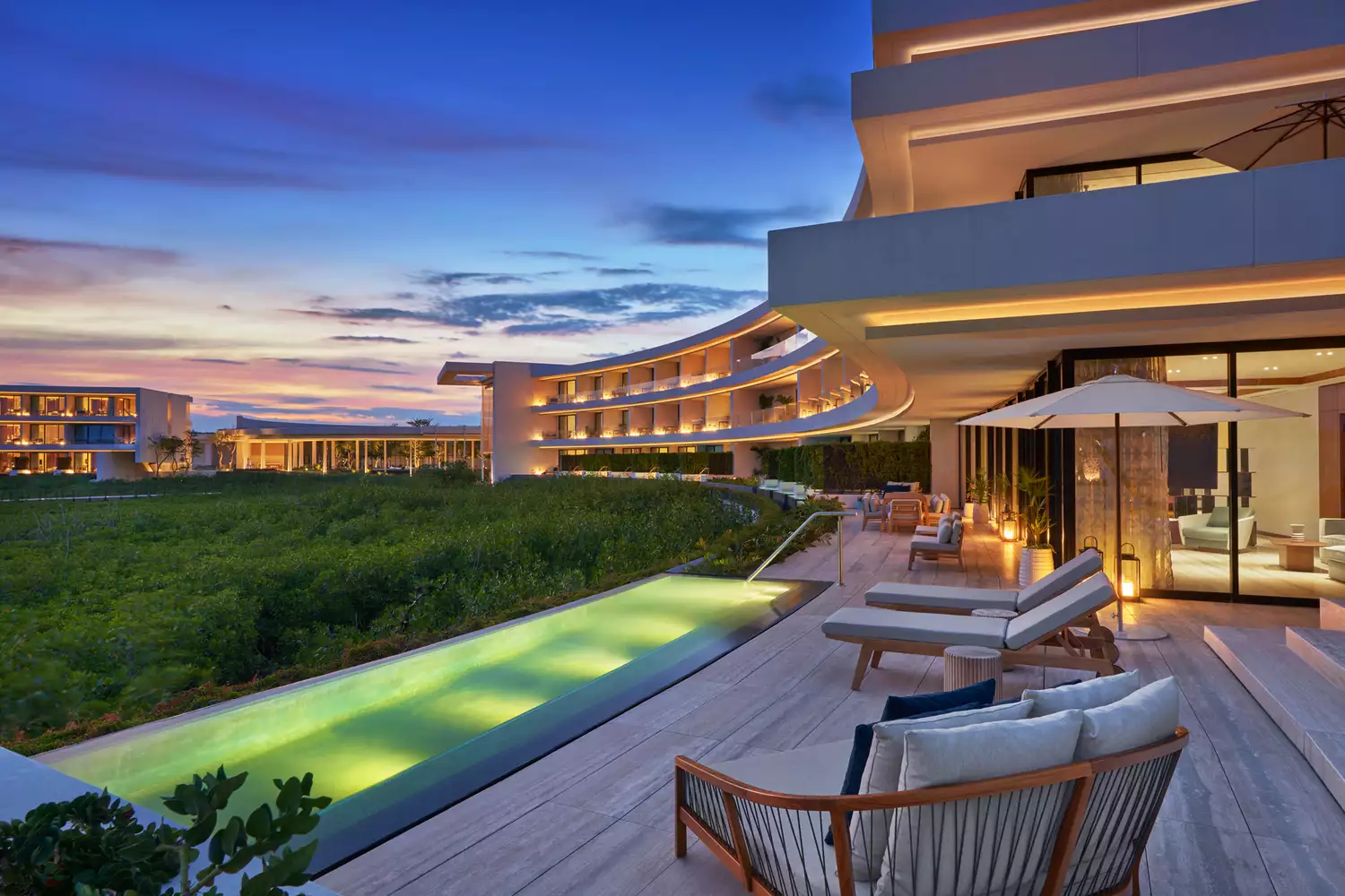 Sophisticated evening lighting on a modern resort patio featuring circular architectural elements and fire pits.