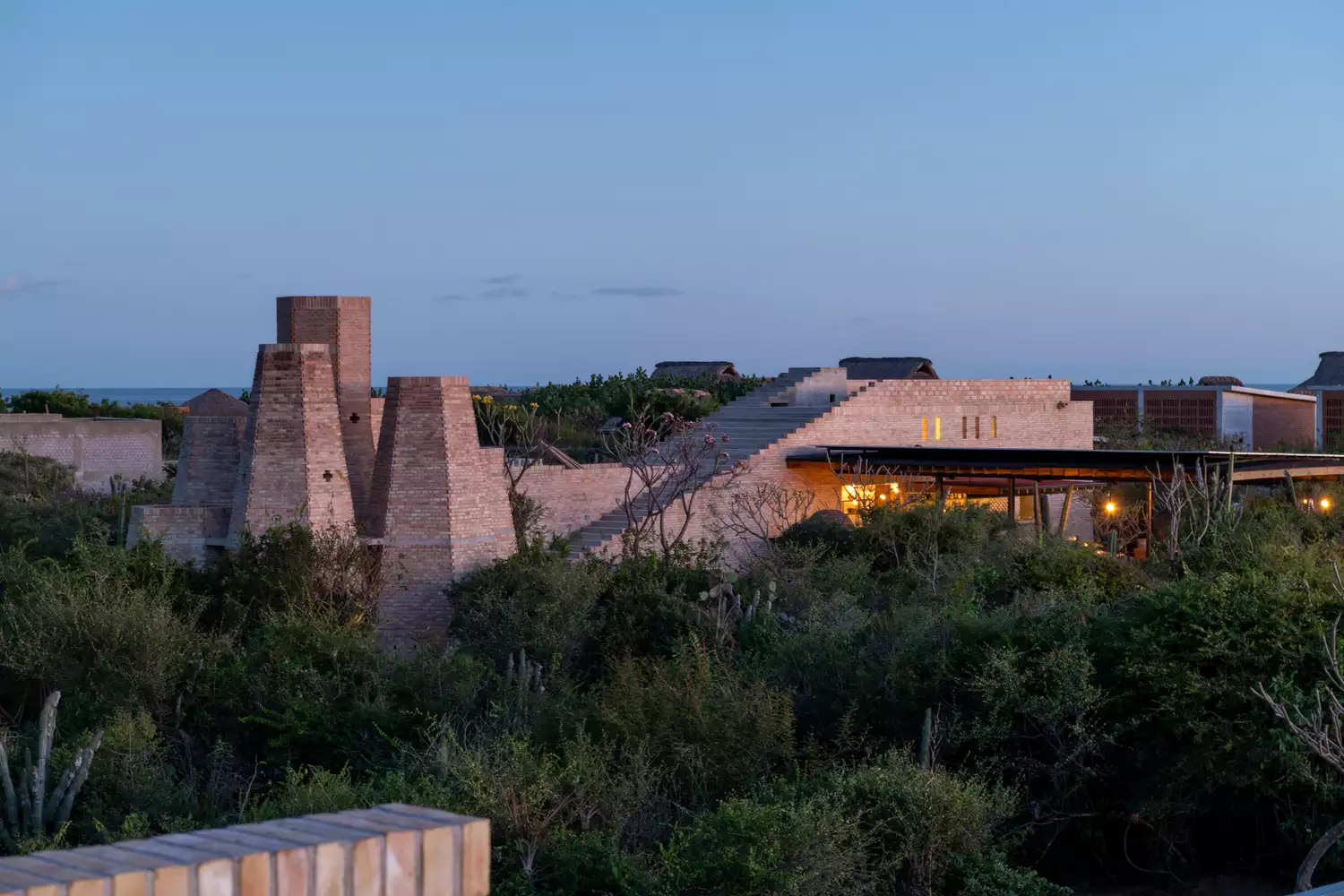 Exterior of a minimalist, brick-constructed hotel at night with warm interior lighting.