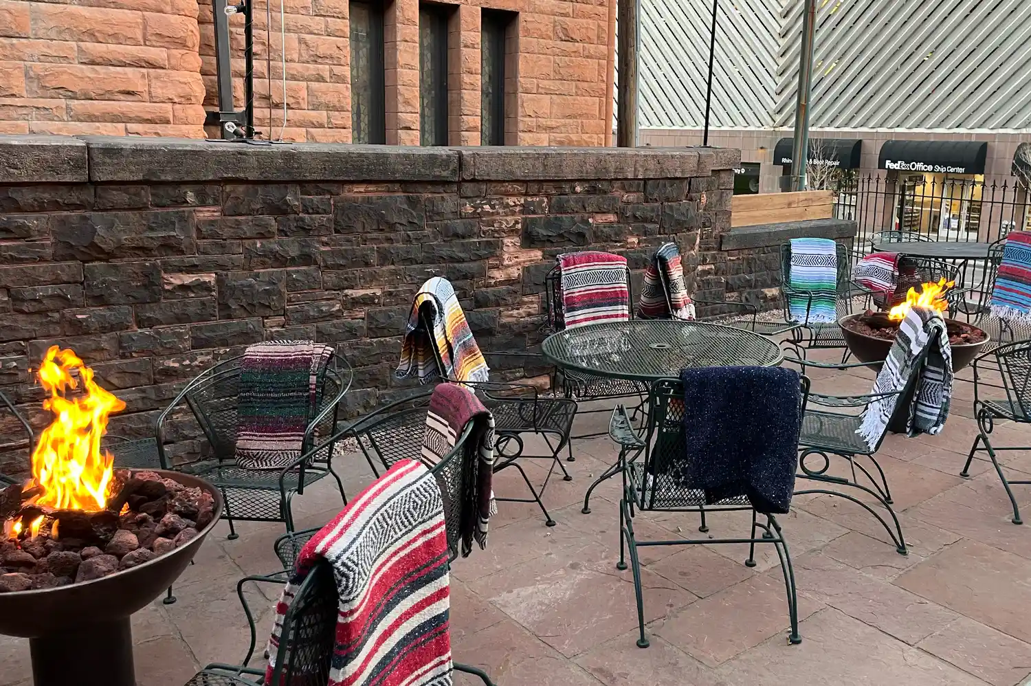 Outdoor patio with fire pits and chairs draped in cozy blankets for guest use.