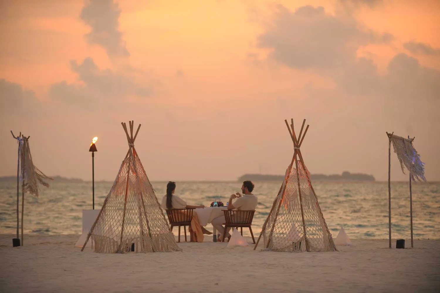 A private sunset dinner set up on a beach in the Maldives for a newlywed couple.