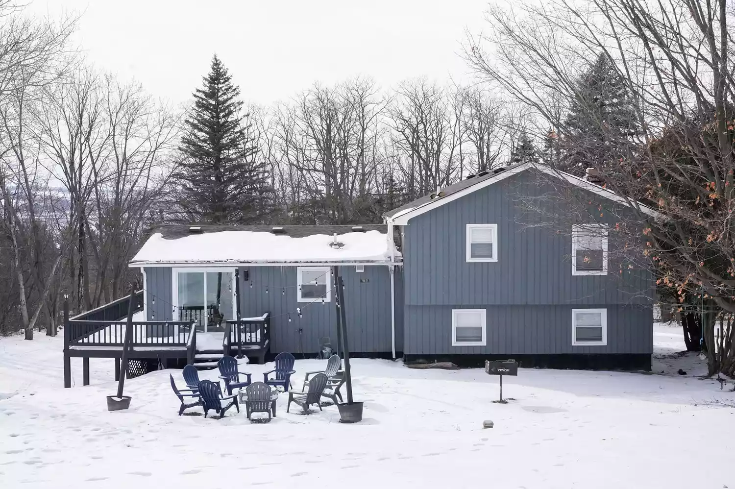 A charming cabin-style house surrounded by deep winter snow in Skaneateles.
